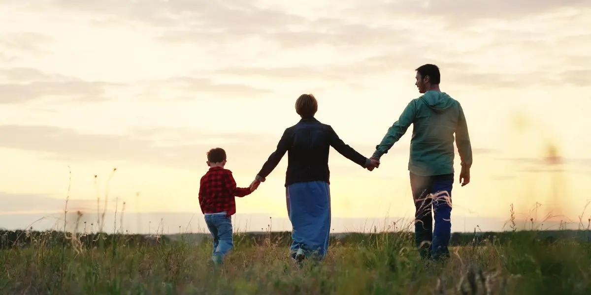 3 pessoas andando de mãos dadas em um campo aberto